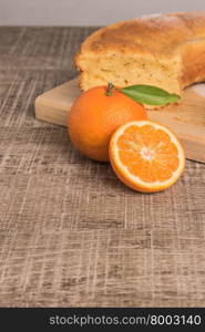 Slices of clementine cake with powdered sugar topping. Cake on a board with fresh clementines on wooden board.