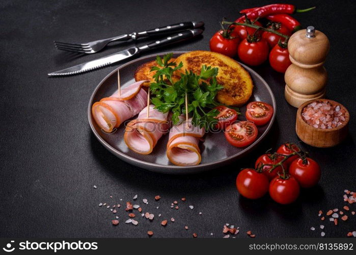 Slices of delicious raw or salted bacon with spices, salt, vegetables and herbs on a wooden cutting board against a dark concrete background. Slices of delicious raw or salted bacon with spices, salt, vegetables and herbs on a wooden cutting board