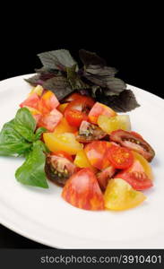 slices of different varieties of tomato with basil on a plate