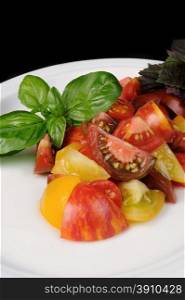 slices of different varieties of tomato with basil on a plate