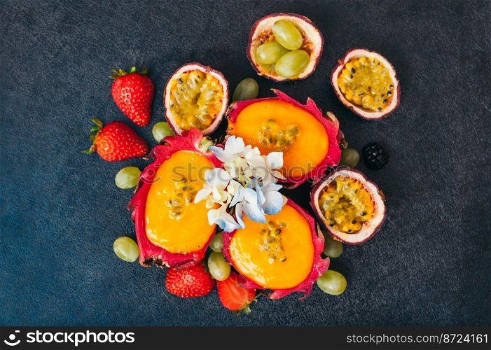 Slices of dragon fruit, red ripe strawberry and grapes on dark background. Set of fresh fruit for making vegeterian salad. Nutrition and vitamins concept