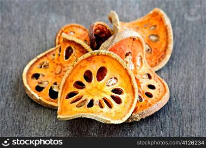 Slices of dried bael fruit on wood surface