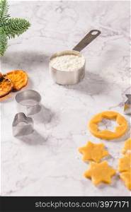 Slices of dried orange and a branch of pine Christmas cookies cutters on marble surface.