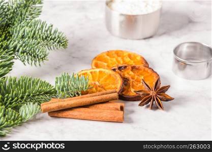 Slices of dried orange and a branch of pine on marble surface.