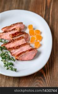 Slices of duck breast with fresh thyme on the white plate