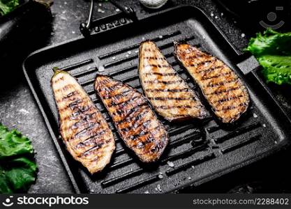 Slices of eggplant in a grill pan. On a black background. High quality photo. Slices of eggplant in a grill pan.