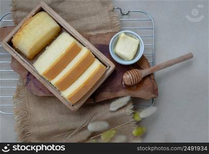 Slices of four butter cakes in wooden box served with butter and honey from above. Selective focus.