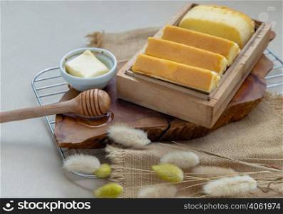Slices of four butter cakes in wooden box served with butter and honey. Selective focus.