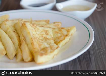 slices of french toast on a white plate served with with sweet sauce. toast