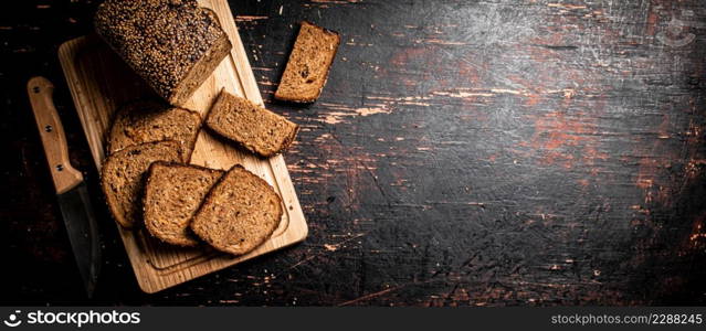 Slices of fresh bread on a wooden cutting board. Against a dark background. High quality photo. Slices of fresh bread on a wooden cutting board.