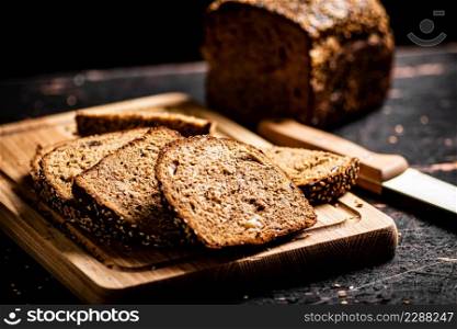 Slices of fresh bread on a wooden cutting board. Against a dark background. High quality photo. Slices of fresh bread on a wooden cutting board.