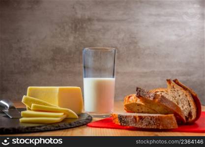 Slices of fresh cheese and bread on a wooden table.  Glass of milk. Organic food. Fresh Bread and Cheese and Glass of Milk
