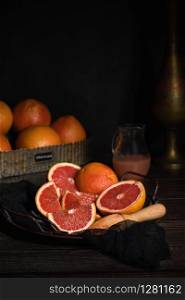Slices of fresh grapefruit prepared for making fresh squeezed juice on a platter, dark background