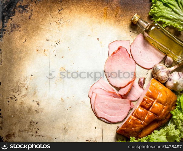 Slices of ham with garlic and herbs . On an old rustic background. Slices of ham with garlic and herbs .