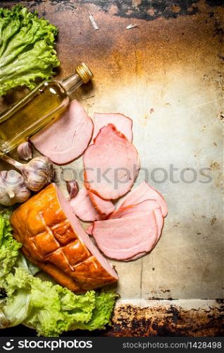 Slices of ham with garlic and herbs . On an old rustic background. Slices of ham with garlic and herbs .