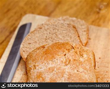 Slices of home made wheat bread on breadboard with knife