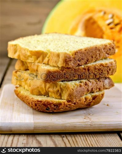 Slices of homemade pumpkin bread, sliced yellow pumpkin on a wooden boards background