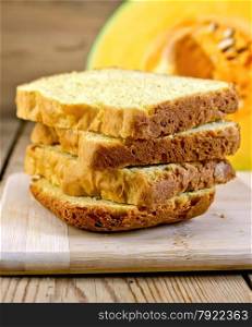 Slices of homemade pumpkin bread, sliced yellow pumpkin on a wooden boards background