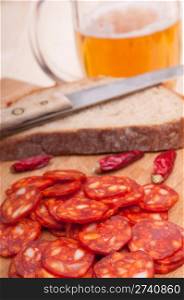 Slices of Hungarian Sausage on Chopping Board With Chilies, Bread and Glass of Beer