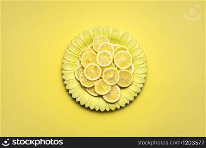 Slices of lemons on a yellow flower-shaped dish on yellow background. Sliced lemons on a plate. A minimalist image in yellow shades. Summer fruits.