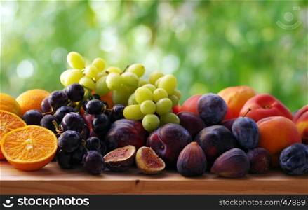 Slices of orange and fig fruits, grapes and plums on table