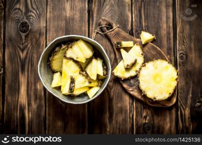 Slices of pineapple in a pot. On a wooden table.. Slices of pineapple in a pot.