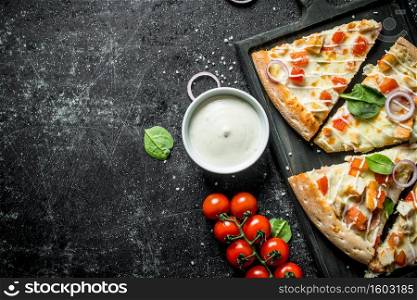 Slices of pizza with tomatoes and cheese sauce in bowl. On dark rustic background. Slices of pizza with tomatoes and cheese sauce in bowl.