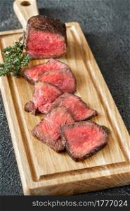 Slices of rare beef steak on the wooden board