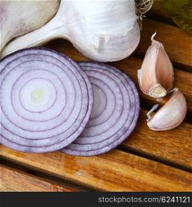slices of red onions and garlic on wooden background