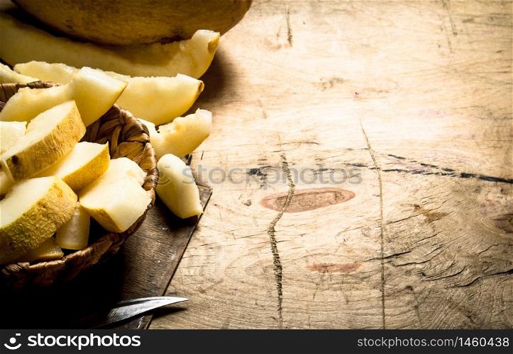 Slices of ripe melon in a basket with a knife. On a wooden table.. Slices ripe melon in a basket