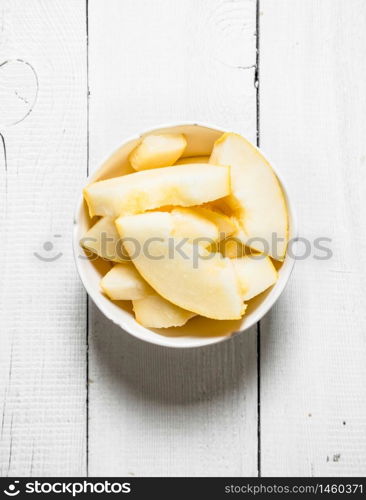 Slices of ripe melon in a bowl. On a white wooden background.. Slices of ripe melon in a bowl.