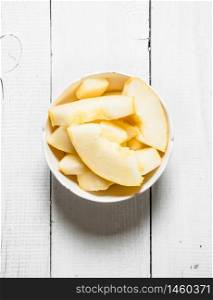Slices of ripe melon in a bowl. On a white wooden background.. Slices of ripe melon in a bowl.