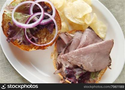 slices of roast beef and red onion on a toasted bun with potato chips