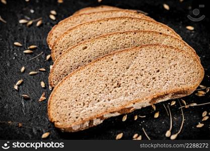 Slices of rye bread with grain on the table. On a black background. High quality photo. Slices of rye bread with grain on the table.