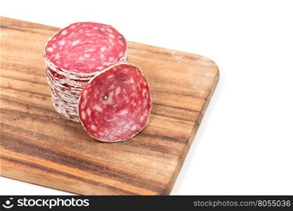 Slices of salami sausages on wooden board isolated