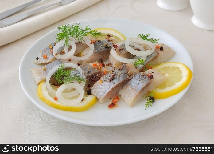 Slices of salted herring fillet with onion, lemon and spices
