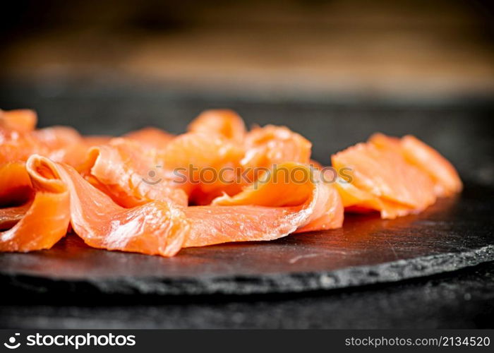 Slices of salted salmon on the table. On a wooden background. High quality photo. Slices of salted salmon on the table.