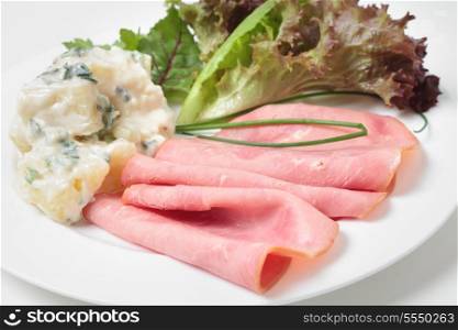 Slices of smoked beef ham served with potato salad and garden fresh vegetables