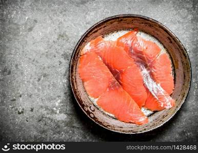 Slices of smoked salmon in the old pan. On a stone background.. Slices of smoked salmon in the old pan.