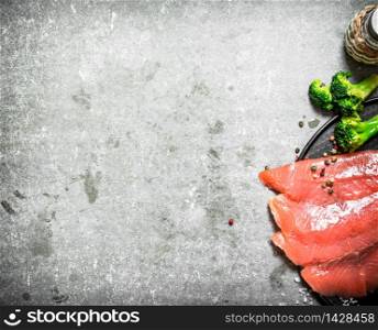 Slices of smoked salmon with broccoli and salt. On a stone background.. Slices of smoked salmon with broccoli and salt.