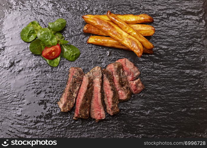 slices of steak with fries on slate