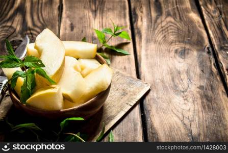 Slices of sweet melon with mint branches. On a wooden table.. Slices of sweet melon with mint branches.