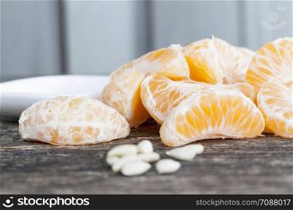 slices of tangerine without peel lying on the table during a meal, close-up of orange citrus, next to it are white bones from the eaten tangerine. slices of tangerine