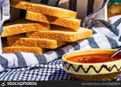 Slices of toast bread in a rustic composition. Blurred bowl with tomato sauce in foreground.