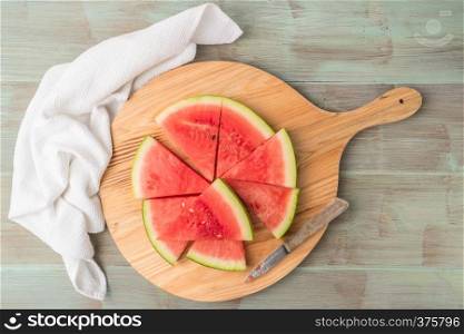 Slices of watermelon on a wood cutting board and wooden background