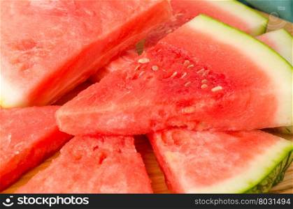 Slices of watermelon on a wood cutting board and wooden background