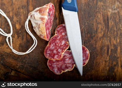 slicing italian salame pressato pressed over old wood table