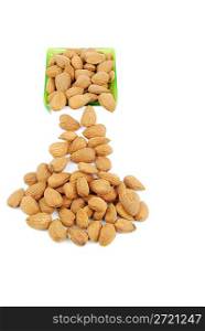 sliding down almond nuts from a green cup isolated on white background