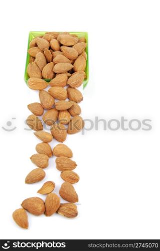 sliding down almond nuts from a green cup isolated on white background