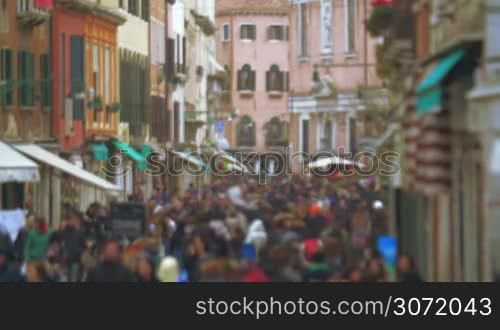 Slight defocus of busy crowded street in the city on dull day. People walking between old vintage buildings in Venice, Italy